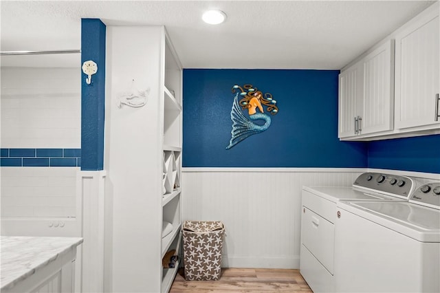 washroom with a wainscoted wall, light wood-style flooring, independent washer and dryer, and cabinet space