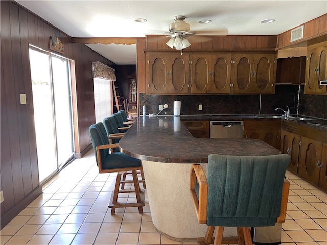 kitchen with backsplash, wooden walls, sink, and a breakfast bar area