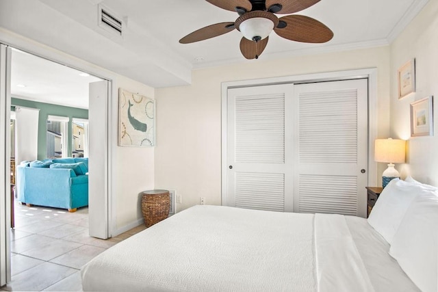 tiled bedroom with a closet, ornamental molding, and ceiling fan