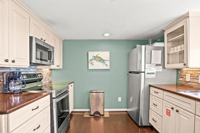 kitchen featuring dark wood-type flooring, appliances with stainless steel finishes, and decorative backsplash