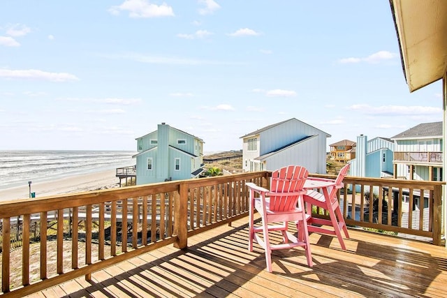 wooden deck featuring a water view and a beach view