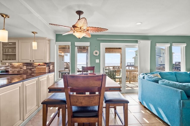 tiled dining space featuring ceiling fan and ornamental molding