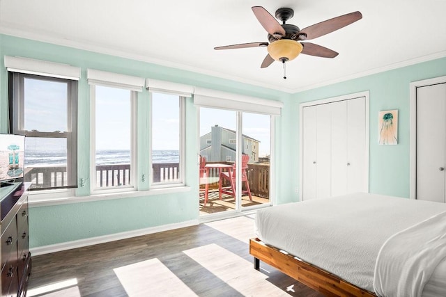 bedroom featuring ceiling fan, dark hardwood / wood-style flooring, ornamental molding, and a water view