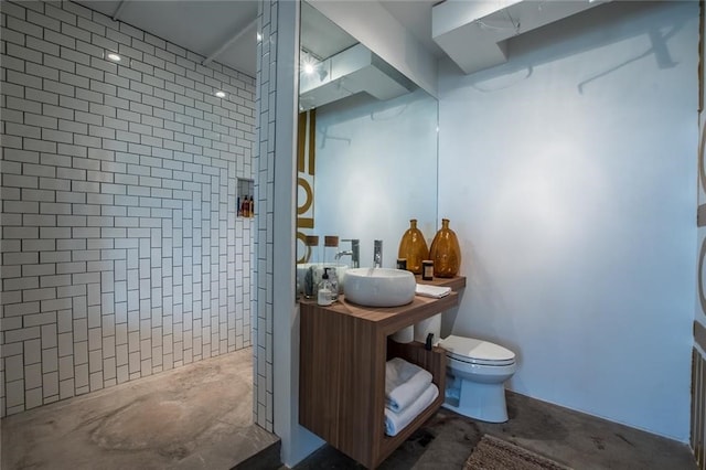 bathroom with concrete flooring, vanity, toilet, and a tile shower