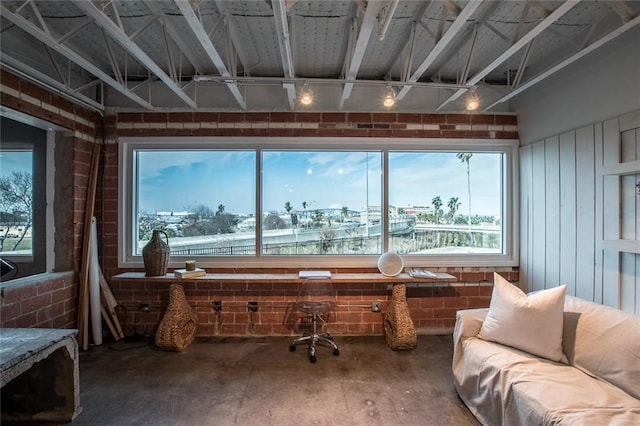 misc room featuring plenty of natural light, a water view, brick wall, and concrete floors