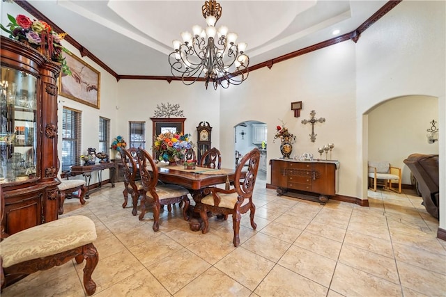 tiled dining room with crown molding, a raised ceiling, an inviting chandelier, and a high ceiling