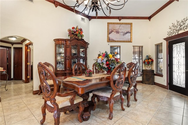 tiled dining area featuring ornamental molding, a towering ceiling, and an inviting chandelier