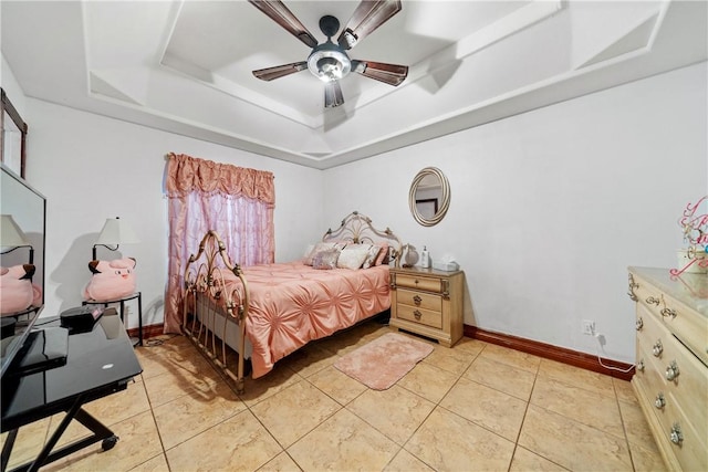 tiled bedroom with ceiling fan and a tray ceiling