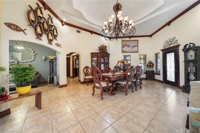 tiled dining room with ornamental molding, a raised ceiling, a high ceiling, and a notable chandelier