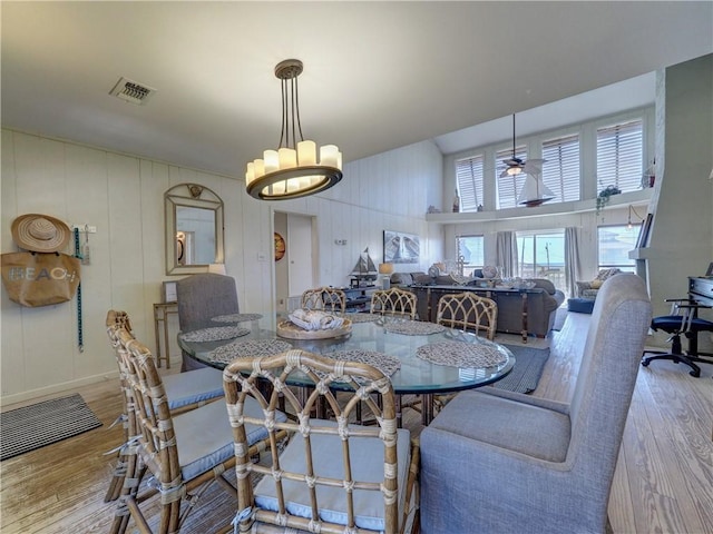 dining area with ceiling fan, light hardwood / wood-style floors, and wood walls