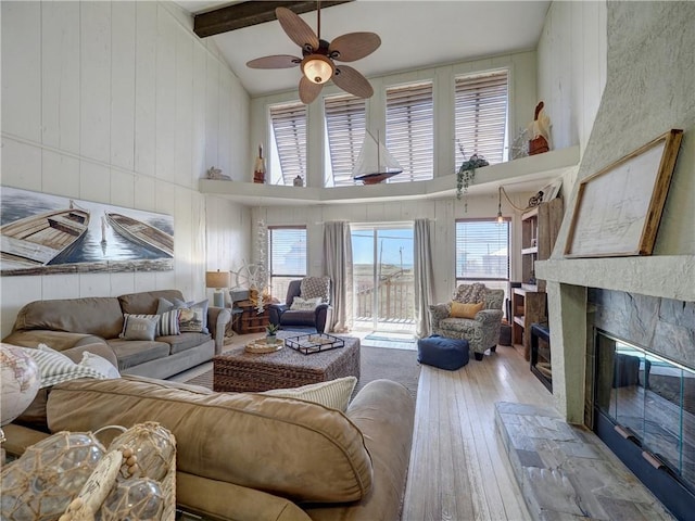 living room with high vaulted ceiling, light wood-type flooring, beamed ceiling, and a healthy amount of sunlight