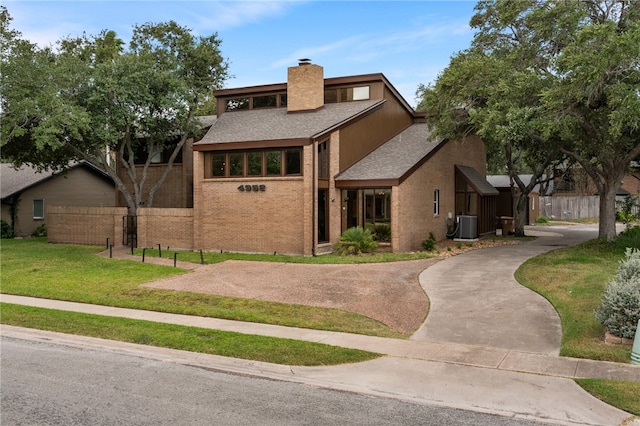 view of front of house with a front lawn and central AC