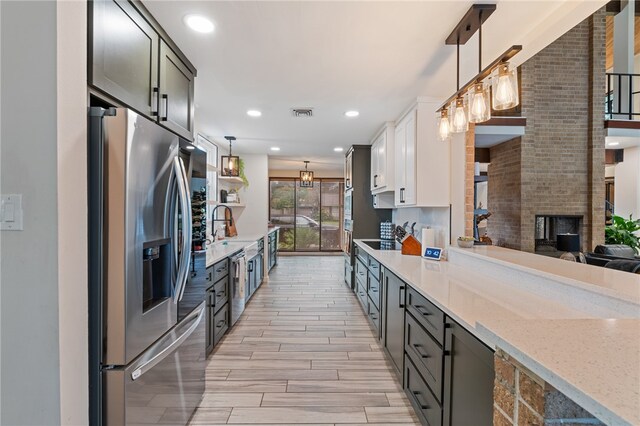 kitchen featuring stainless steel appliances, white cabinets, pendant lighting, and light hardwood / wood-style flooring