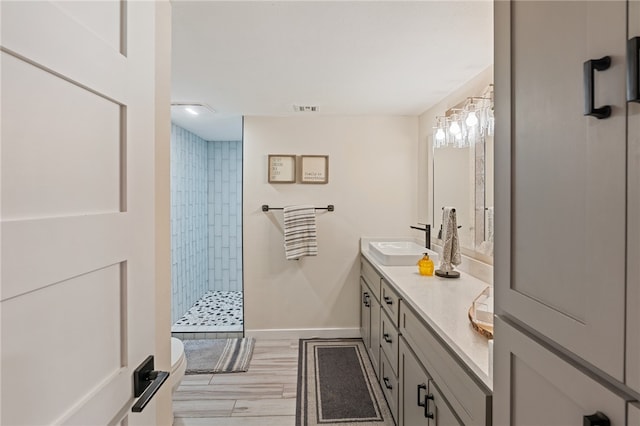 bathroom with tiled shower, vanity, and hardwood / wood-style flooring