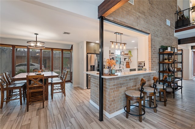 kitchen featuring light wood-type flooring, a breakfast bar area, pendant lighting, and kitchen peninsula