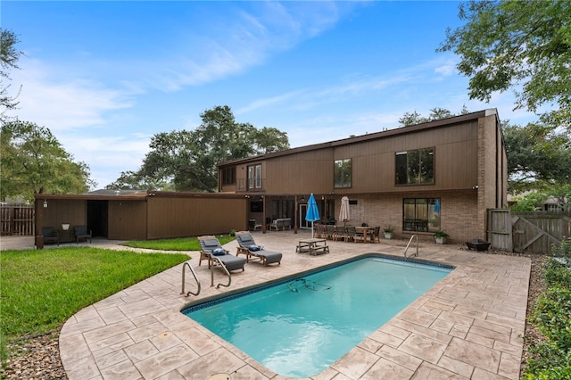 back of property with a fenced in pool and a patio area