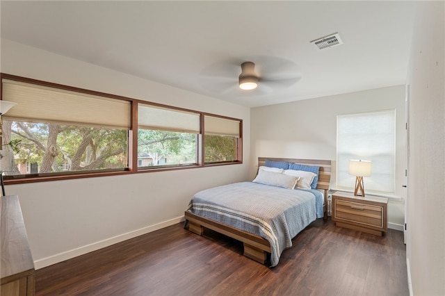 bedroom featuring multiple windows, dark hardwood / wood-style floors, and ceiling fan