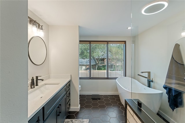 bathroom with a tub to relax in, vanity, tile patterned floors, and toilet