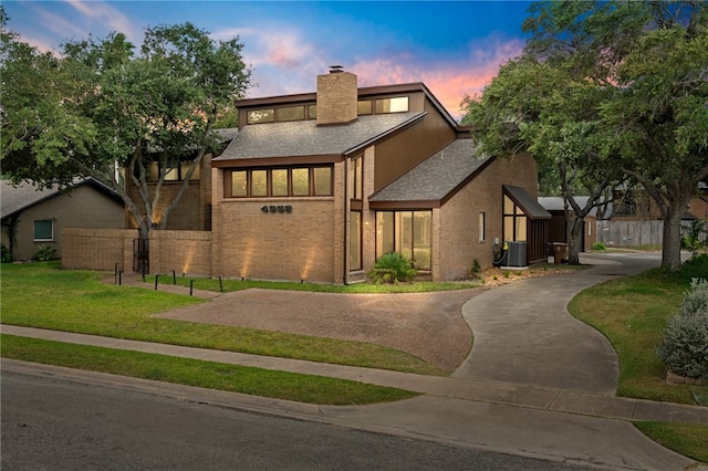 view of front of property featuring central AC unit and a lawn