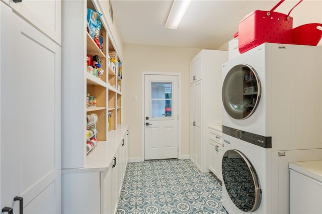 washroom with stacked washing maching and dryer and cabinets