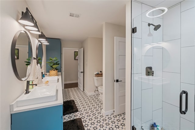 bathroom featuring a shower with shower door, vanity, and toilet