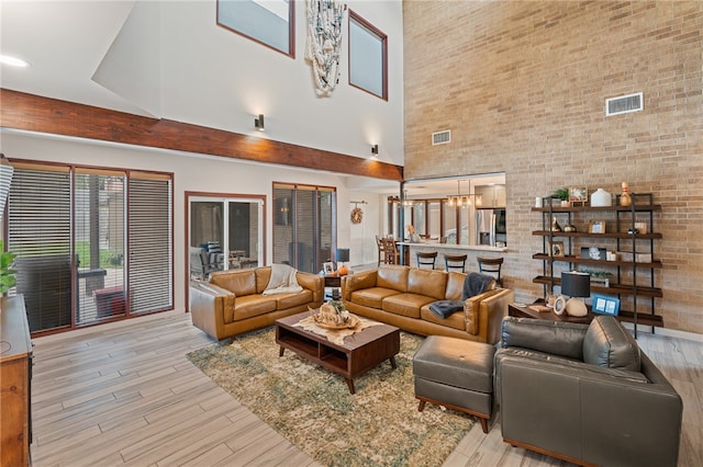 living room featuring a high ceiling, a chandelier, and light hardwood / wood-style floors