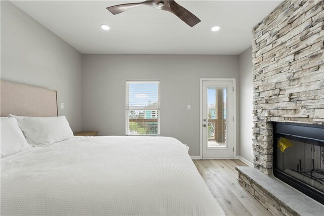 bedroom featuring access to exterior, a fireplace, baseboards, light wood-style floors, and ceiling fan