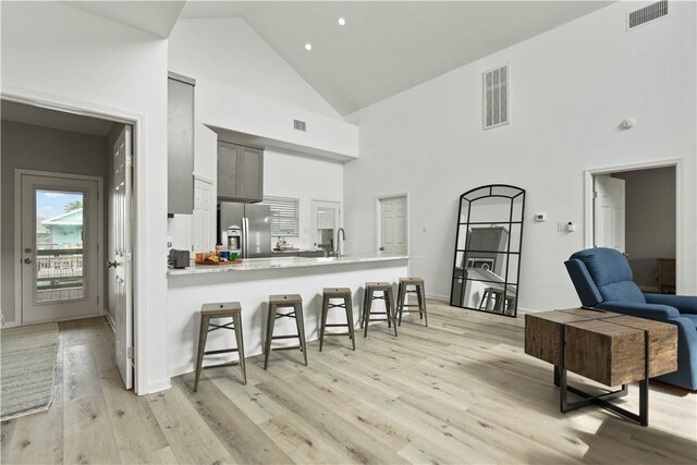 kitchen featuring a kitchen bar, stainless steel fridge, visible vents, light wood-style flooring, and a peninsula