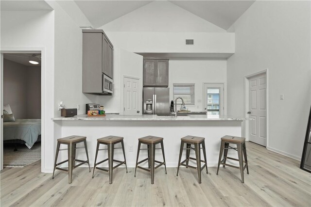 kitchen featuring visible vents, light wood-style floors, a kitchen bar, and stainless steel appliances