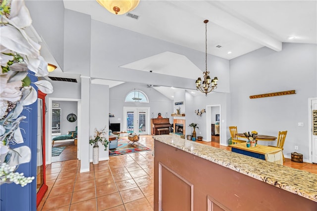 kitchen with french doors, a notable chandelier, light tile patterned floors, high vaulted ceiling, and decorative light fixtures