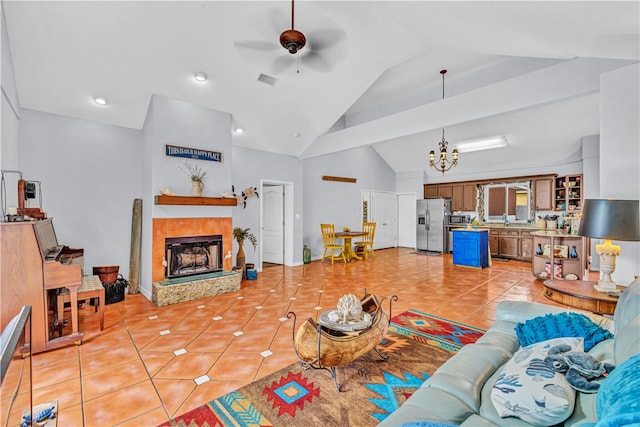 living room with ceiling fan with notable chandelier, a tiled fireplace, lofted ceiling, and light tile patterned floors