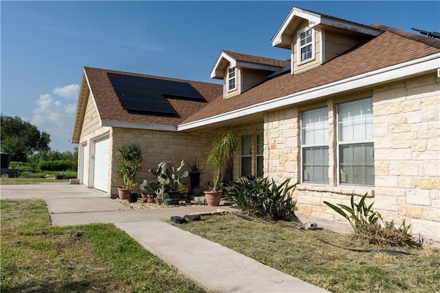 view of front facade featuring solar panels and a garage