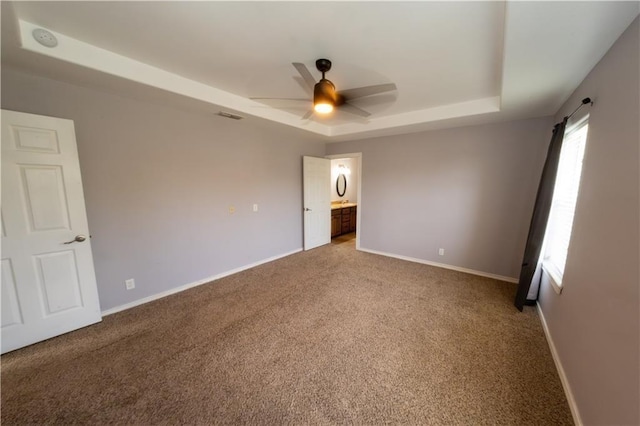 unfurnished room with carpet, ceiling fan, and a tray ceiling