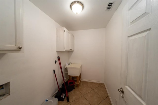 laundry area featuring hookup for an electric dryer, cabinets, and light tile patterned floors