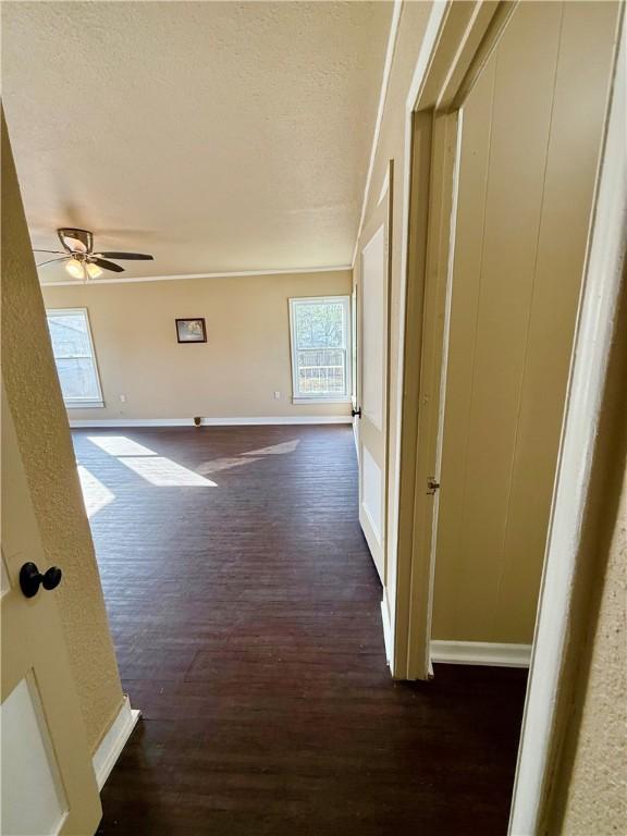 hallway with baseboards, dark wood finished floors, and a textured ceiling