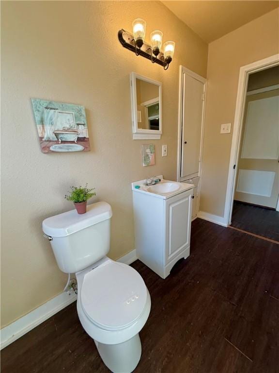 bathroom with vanity, wood finished floors, toilet, and baseboards