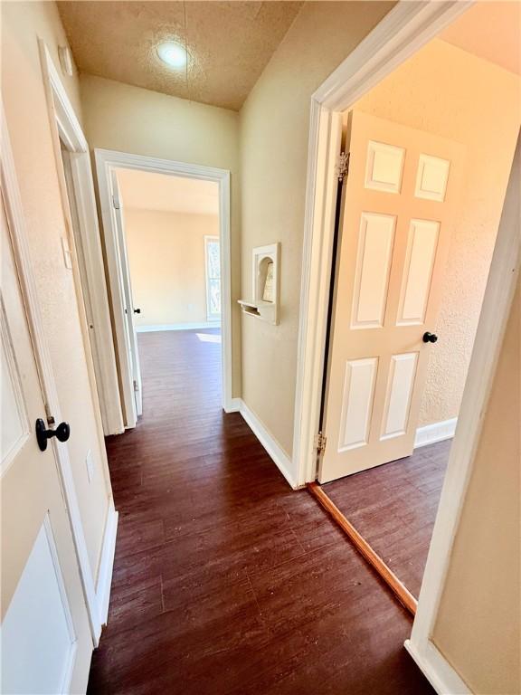 hall featuring dark wood-style floors and baseboards