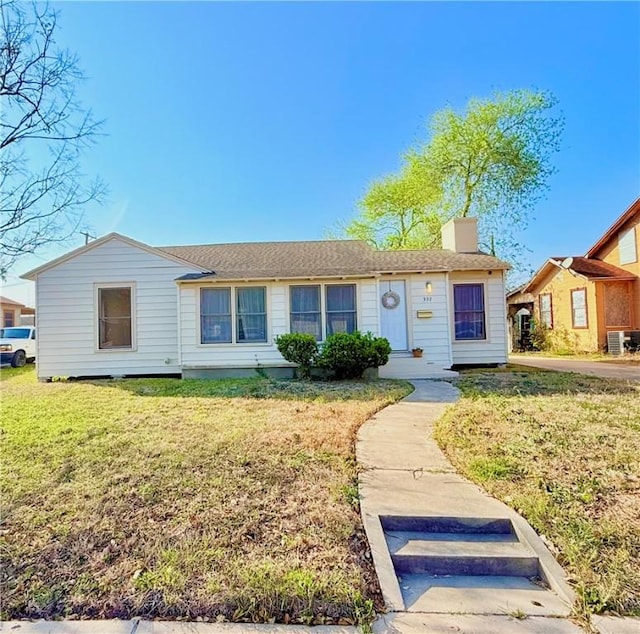 ranch-style house with cooling unit, a chimney, and a front lawn