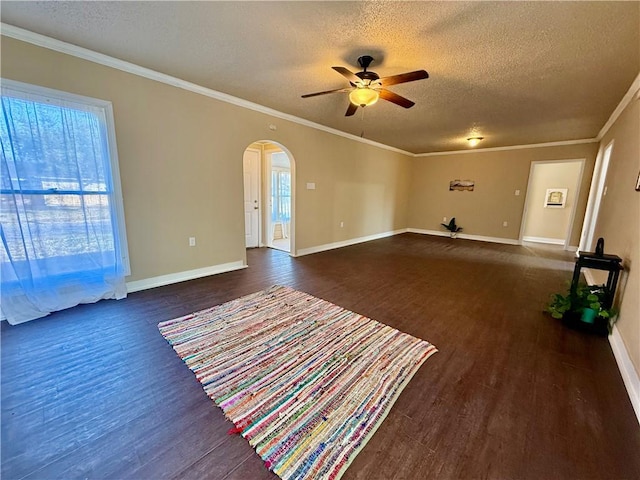 unfurnished living room with arched walkways, ceiling fan, a textured ceiling, dark wood-style floors, and crown molding