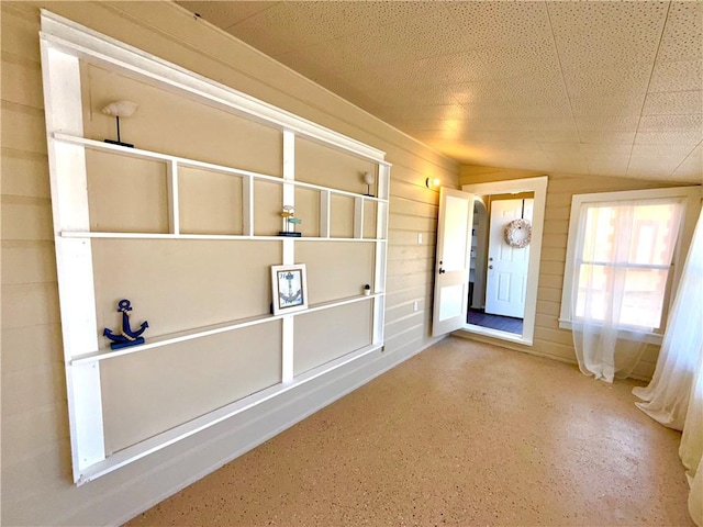 interior space featuring lofted ceiling and wooden walls