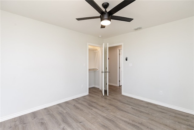 unfurnished bedroom with ceiling fan, a closet, light wood-type flooring, and a spacious closet