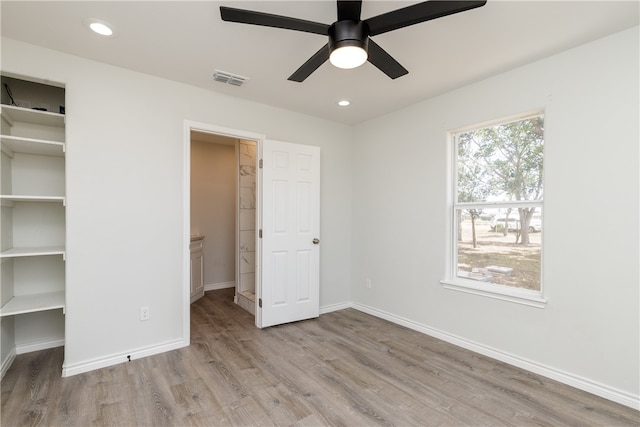 unfurnished bedroom with light hardwood / wood-style flooring, ceiling fan, and a walk in closet