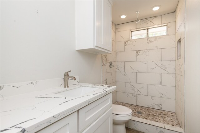 bathroom featuring tiled shower, toilet, and vanity