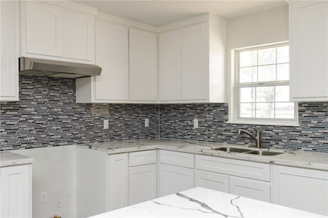 kitchen featuring light stone counters, sink, backsplash, white cabinetry, and range hood