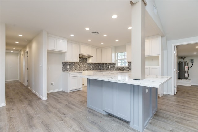 kitchen with white cabinetry, light stone counters, a center island, and light hardwood / wood-style flooring