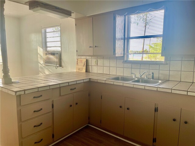 104 E Refugio St, Skidmore, TX 78389 - kitchen with a peninsula, decorative backsplash, tile countertops, and dark wood-style flooring