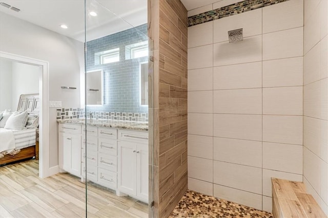 ensuite bathroom with connected bathroom, visible vents, recessed lighting, vanity, and tiled shower