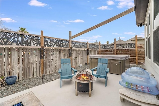 view of patio featuring a fenced backyard, an outdoor fire pit, and a hot tub