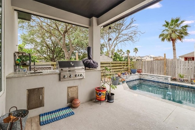 view of swimming pool with exterior kitchen, a patio area, grilling area, a sink, and fence