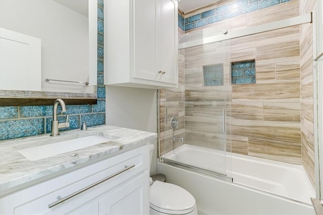 full bath featuring combined bath / shower with glass door, vanity, toilet, and decorative backsplash